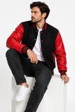Black-and-red varsity jacket styled on a male model in a seated editorial studio pose